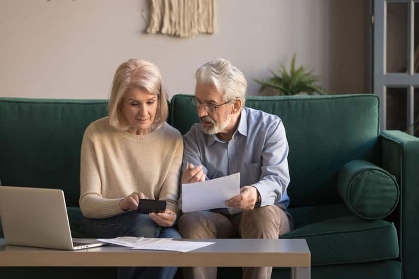 serious mature couple calculating bills, checking domestic finances